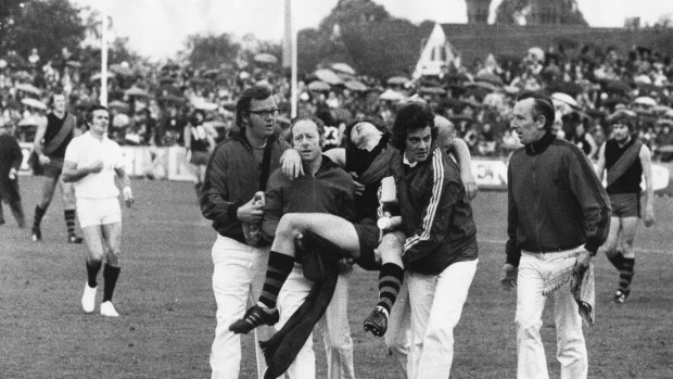 Essendon back pocket player Dean Hartigan slumps unconscious after an incident behind play.