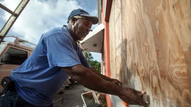 A worker boards up a restaurant as Bermudans prepare for the arrival of Hurricane Gonzalo in Flatts Village.