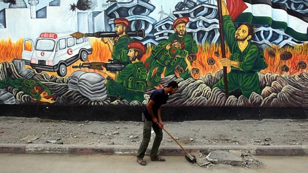 A street sweeper at work in Gaza City. Behind him, a mural tells its own story. Gaza's economy is paralysed, there is a growing water crisis, and life is almost unbearable.