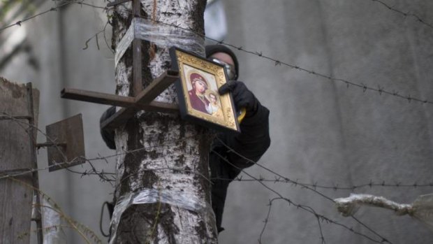 A pro-Russian activist puts an icon on top of barricades in the eastern city of Slaviansk.