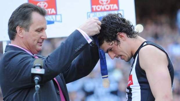Scott Pendlebury receives the Norm Smith medal from Arnold Briedis, a star of the 1977 grand final rematch.