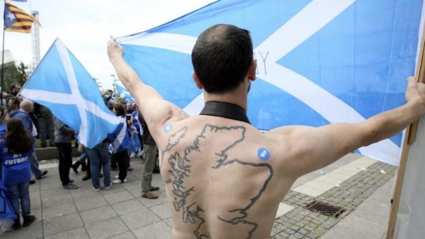 A 'yes' campaigner with a tattoo of Scotland on his back holds the Saltire aloft in Glasgow.