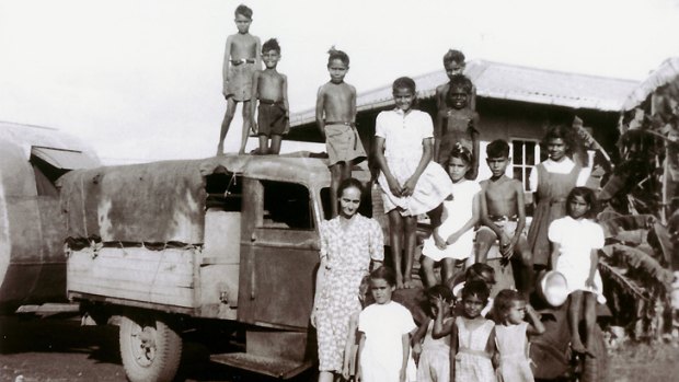Mixed-race Aboriginal children living at Retta Dixon home in Darwin. Lorna Cubillo, aged about 9, is in the white dress at far right sitting on the bumper over the wheel. Mrs Long, a missionary, is with the children.