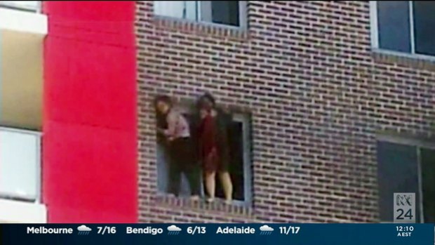 Yinou "Ginger" Jiang and Pingkang "Connie" Zhang cling to the side of their apartment building before being forced to jump.