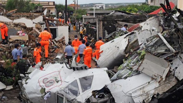 Rescue workers and firefighters search through the wreckage where TransAsia Airways flight GE222 crashed.