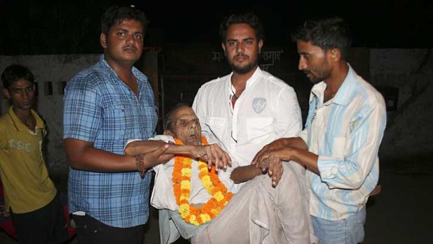 Brij Bihari Pandey, 108, is assisted by relatives following his release from an Indian jail.