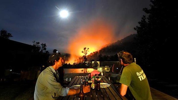 Fires in the Alpine National Park at Harrietville. Justin Crawley (left) watches the fire with Andy Forbes after finishing dinner.
