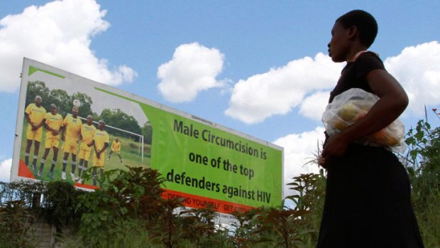 A Zimbabwean woman walks past a billboard promoting male circumcision to combat Aids in the capital, Harare. Fear of infection and mass social change have driven a huge decline in HIV rates in Zimbabwe.