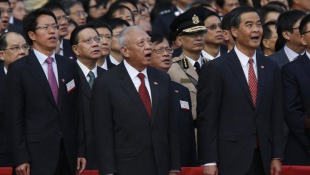 Director of the Liaison Office of the Central People's Government in Hong Kong, Zhang Xiaoming; former Hong Kong chief executive Tung Chee-hwa; and Hong Kong Chief Executive Leung Chun-ying sing the national anthem during a flag-raising ceremony.