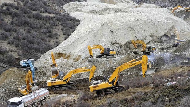 Remote: Earthmovers remove rocks at the site of the landslide.