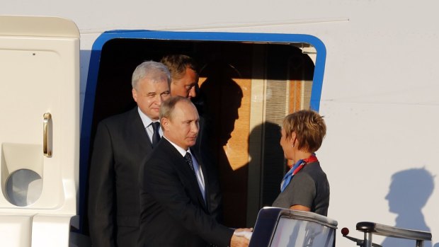 Russian President Vladimir Putin, foreground left, shakes hands with an aircrew member upon his arrival at the Beijing Capital International Airport in Beijing on Wednesday.
