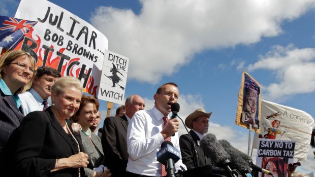Tony Abbott as opposition leader in front of posters at a ant-carbon tax rally.