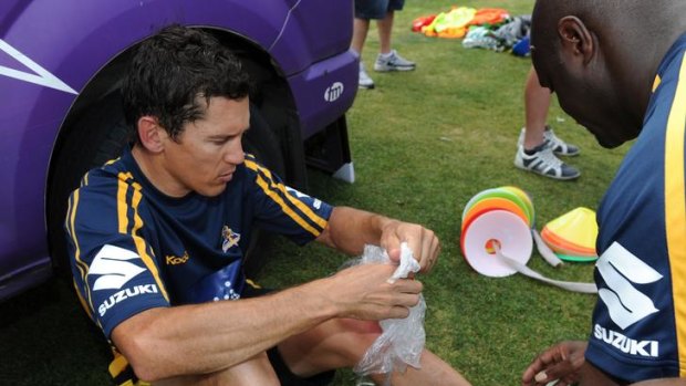 Knees up: Robbie McEwan and a trainer inspect his injured knee after some drills with Melbourne Storm yesterday.