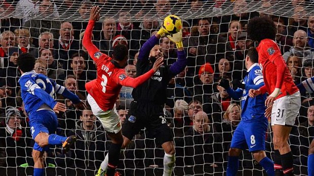 Everton's US goalkeeper Tim Howard (C) saves from Manchester United's French defender Patrice Evra (2L).