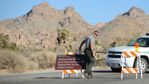 An US Park Ranger sets up a sign announcing the closure of Joshua Tree National Park, in Joshua Tree, California.