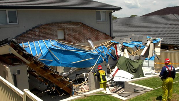 Emergency service workers among the wreckage of the house's patio following the plane crash in suburban Sydney.