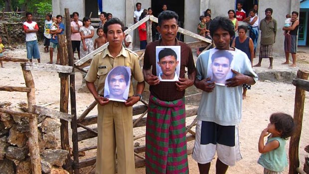 Relatives of the imprisoned boys hold pictures of John Ndollu,  Ose Lani and Ako Lani in the Indonesian village of Manamolo.