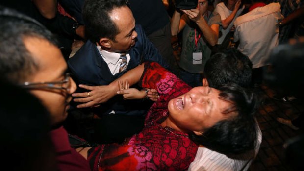 A Chinese relative of a passenger aboard the missing MH370 is carried out of a press conference by security officials.