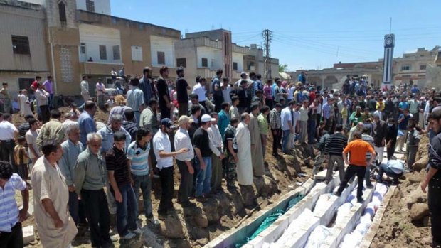 Response to an atrocity ... mourners gather at a mass burial for the victims of Houla.
