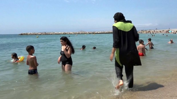 Nissrine Samali, 20, gets into the sea fully clothed in Marseille, southern France. The Cote d'Azur city of Cannes has banned full-body swimsuits dubbed 'burqinis'. 