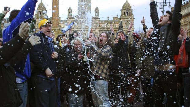 Revellers spray a bottle of champagne in Glasgow.