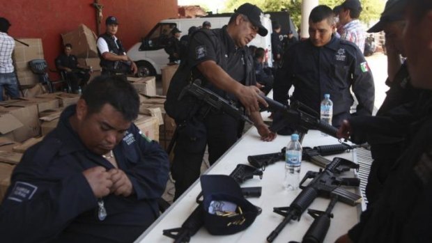 Former vigilantes receive weapons during a swearing in ceremony as members of the Fuerza Rural Estatal, which will fight against Servando Gomez's gang Knights Templa.