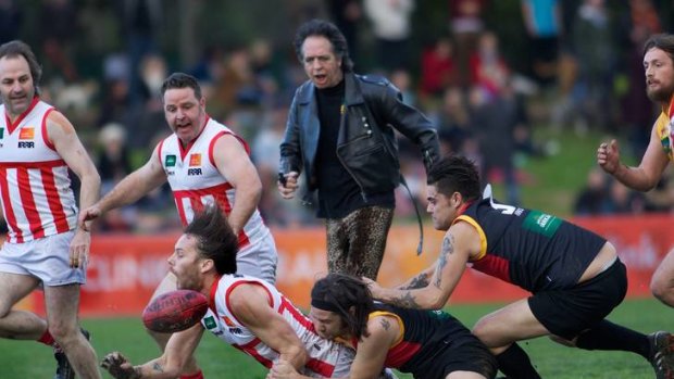 Rockdog Dan Sultan slides in to halt the Megahertz attack as RocKwiz host and umpire Brian Nankervis looks on during Sunday's Community Cup.