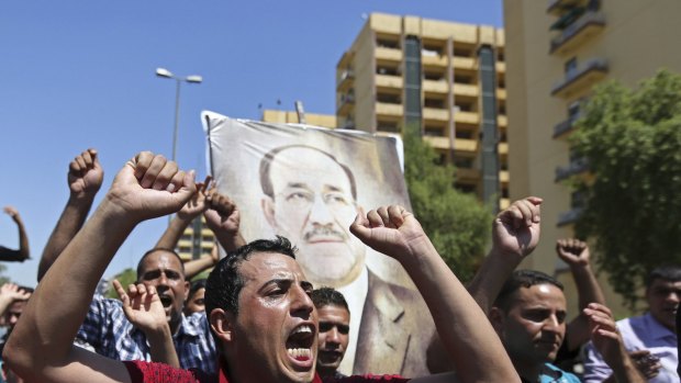 Iraqis chant pro-government slogans bearing a picture of embattled Prime Minister Nouri al-Maliki in Baghdad on Monday.