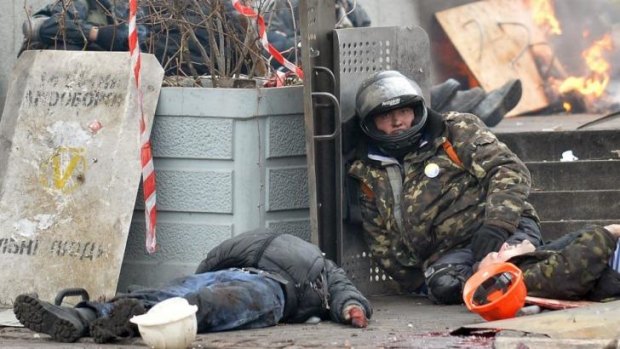 A wounded pro-European Maidan self-defence activist next to the bodies of people killed by snipers in Institutskaya Street, Kiev in February. 