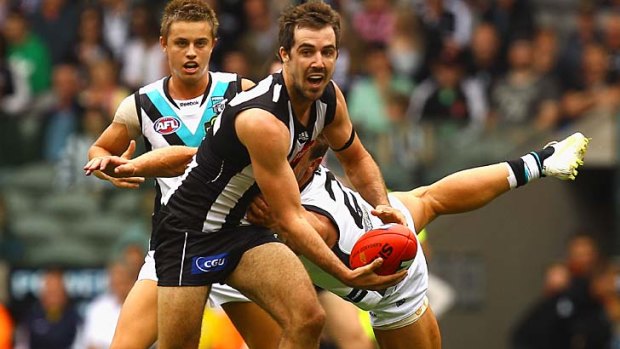 Collingwood's Steele Sidebottom breaks a tackle by Matt Thomas during the match between Collingwood and Port Adelaide in Melbourne.