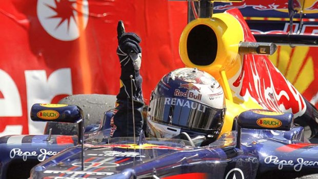 Sebastian Vettel raises his hand in triumph as he takes the chequered flag.