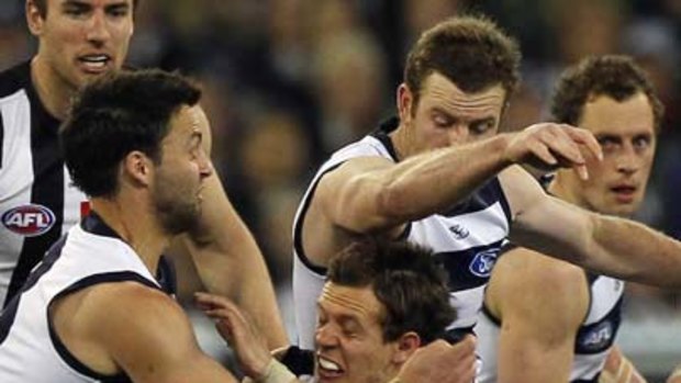 Luke Ball is sandwiched by Cats Jimmy Bartel and Steve Johnson.