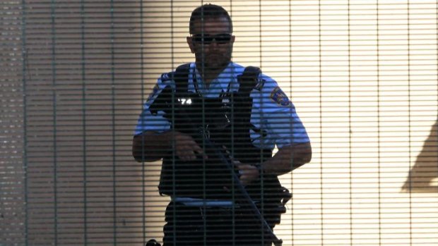 A heavily armed police officer prepares to escort Omarjan Azari at Sydney's Central Local Court.