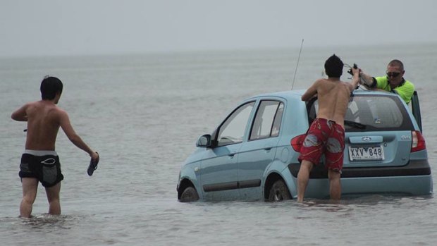The tourists retrieve belongings from their stranded hire car.