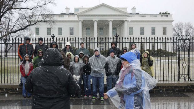 A tour group poses for a photo in front of the White House. The US government has cancelled its visitor tours of the building due to budget cuts.