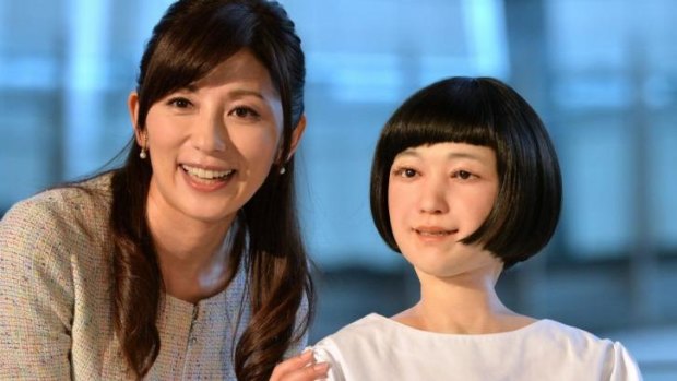 Japanese announcer Aki Nakata (left) smiles as she poses with a new humanoid robot named "Kodomoroid" at the National Museum of Emerging Science and Technology in Tokyo.