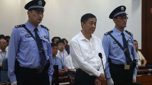 Bo Xilai in court, flanked by two policemen.
