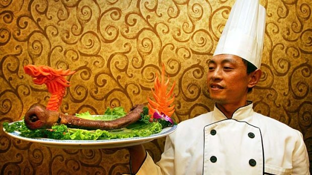 A cook poses with a plate of yak penis at the Guolizhuang Penis Restaurant in Beijing, China.