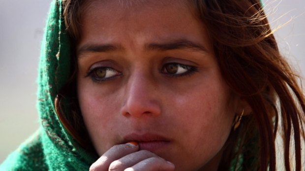 Under fire...an Afghan girl waits to receive food and  blankets in the Alassay Valley.