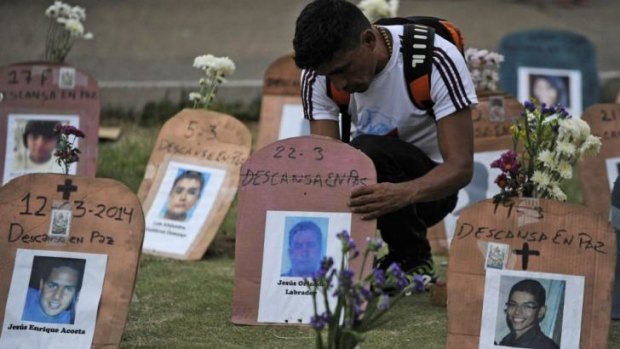 A man arranges tombstones with pictures of dead protesters in Caracas.