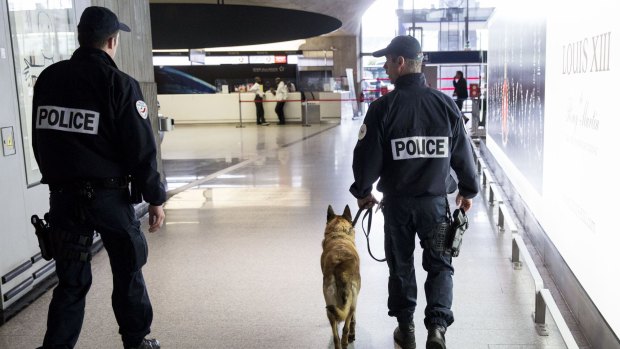 French police officers and a sniffer dog patrol a terminal building at Charles de Gaulle airport on Thursday.