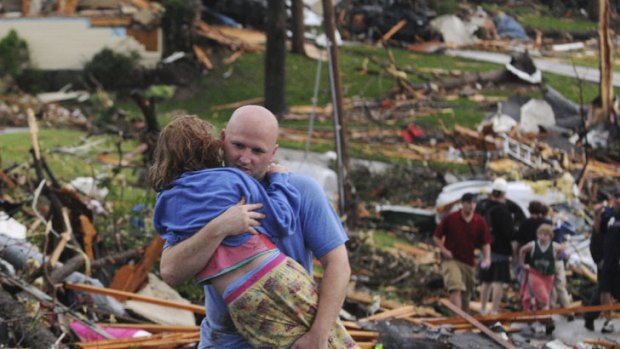 A man carries a young girl who was rescued after being trapped with her mother in their home in Joplin