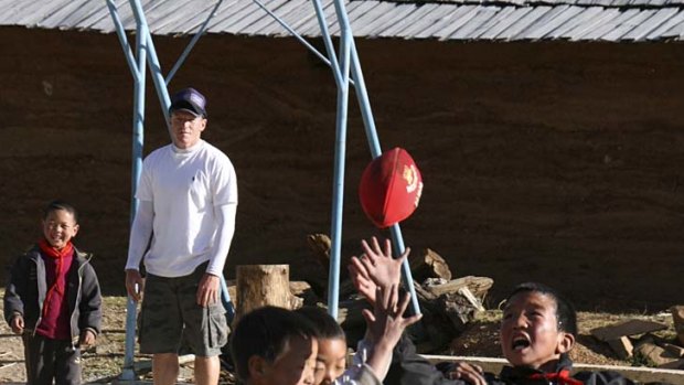 Lifting spirits: Swans' Jared Crouch watches Chinese children play with a football he and teammate Ryan O'Keefe gave them.
