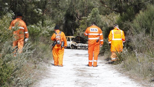 SES volunteers examine the scene of a burnt-out car which was linked to Mr Colbung's disappearance last week.