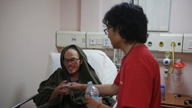 A family member gives water to Liang Sheng-yueh at the Grande Hospital in Kathmandu.