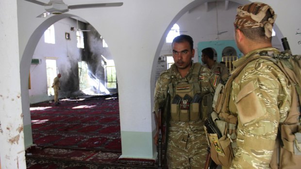 Iraqi security forces stand inside a mosque at the site of a suicide bomber attack in the town of Wajihiya.