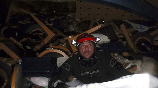 A scuba diver makes his way through floating pieces of furniture inside the cruise ship.