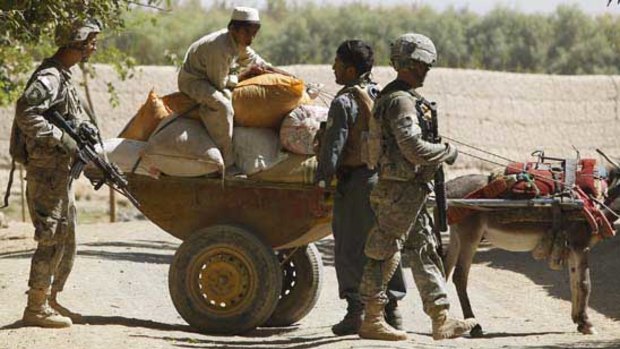 US soldiers and an Afghan policeman check a donkey cart in a village in Kandahar province.