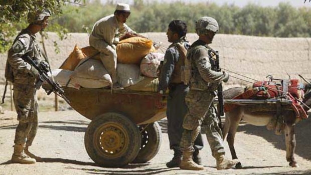 US soldiers and an Afghan policeman check a donkey cart in a village in Kandahar province.