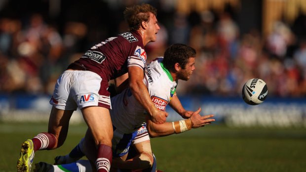 Shaun Fensom of the Raiders offloads the ball as he is tackled by the Sea Eagles.